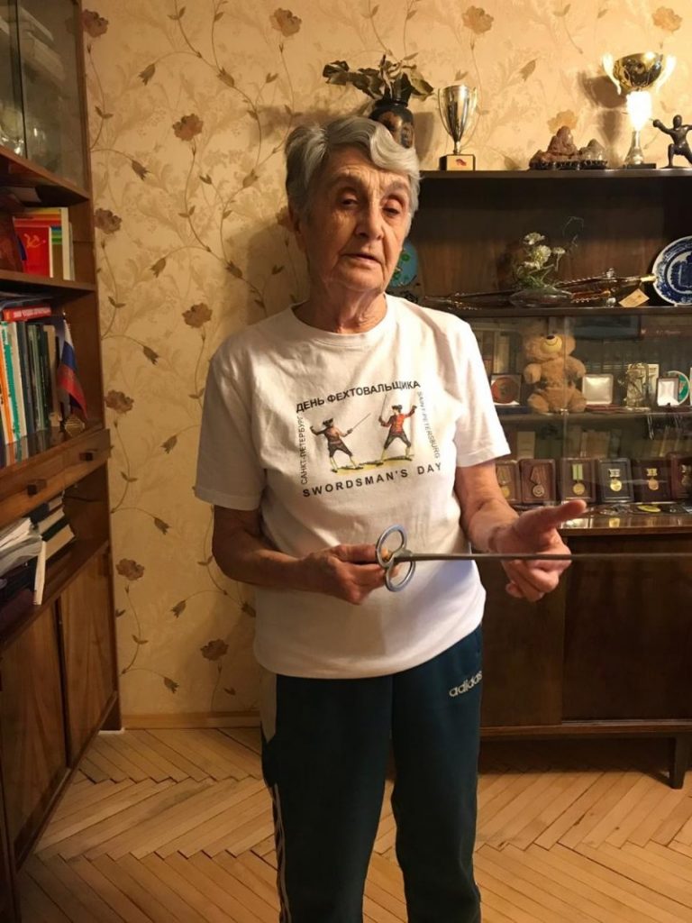 Таджиева Ксения Аркадьевна поддерживает праздник День Фехтовальщика с первого дня в 2005 году. На фото она в футболке праздника и с исторической рапирой, подаренной СПб Фехтовальным Клубом в честь 85-летнего юбилея.